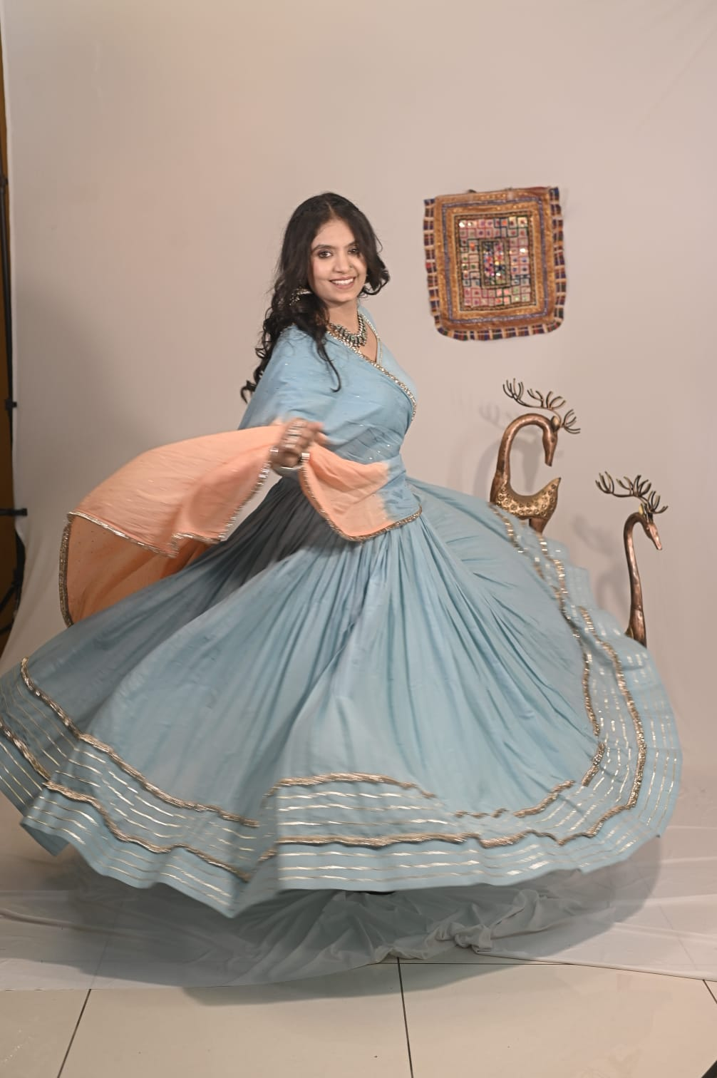 Model twirling in the Sky Blue Chaniya Choli with peach dupatta